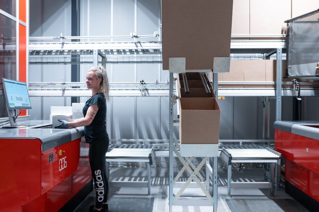 Warehouse worker standing at AutoStore station with box